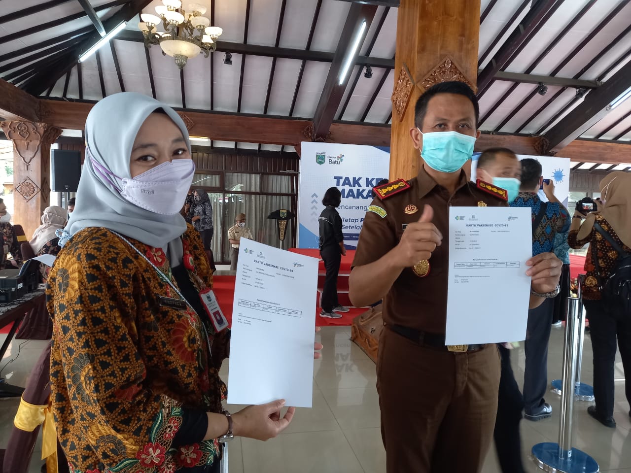 Kadinkes Kota Batu Kartika Trisulandari (kiri) menunjukkan kartu vaksinasi Covid-19. (Imam N/Radar Malang)