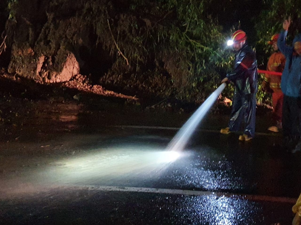 Petugas BPBD dan tim Damkar Kota Batu saat membersihkan material longsor malam ini. (5/2) (BPBD Kota Batu for Radar Malang)