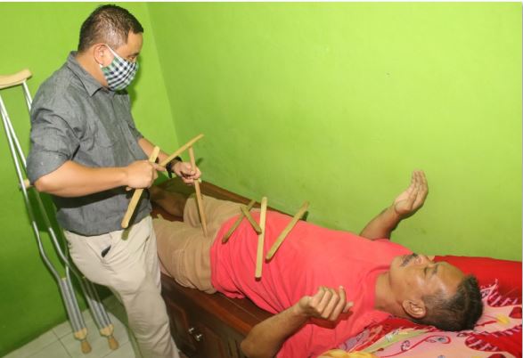 Agus saat mengobati salah satu pasien (Laoh Mahfud / Radar Malang)