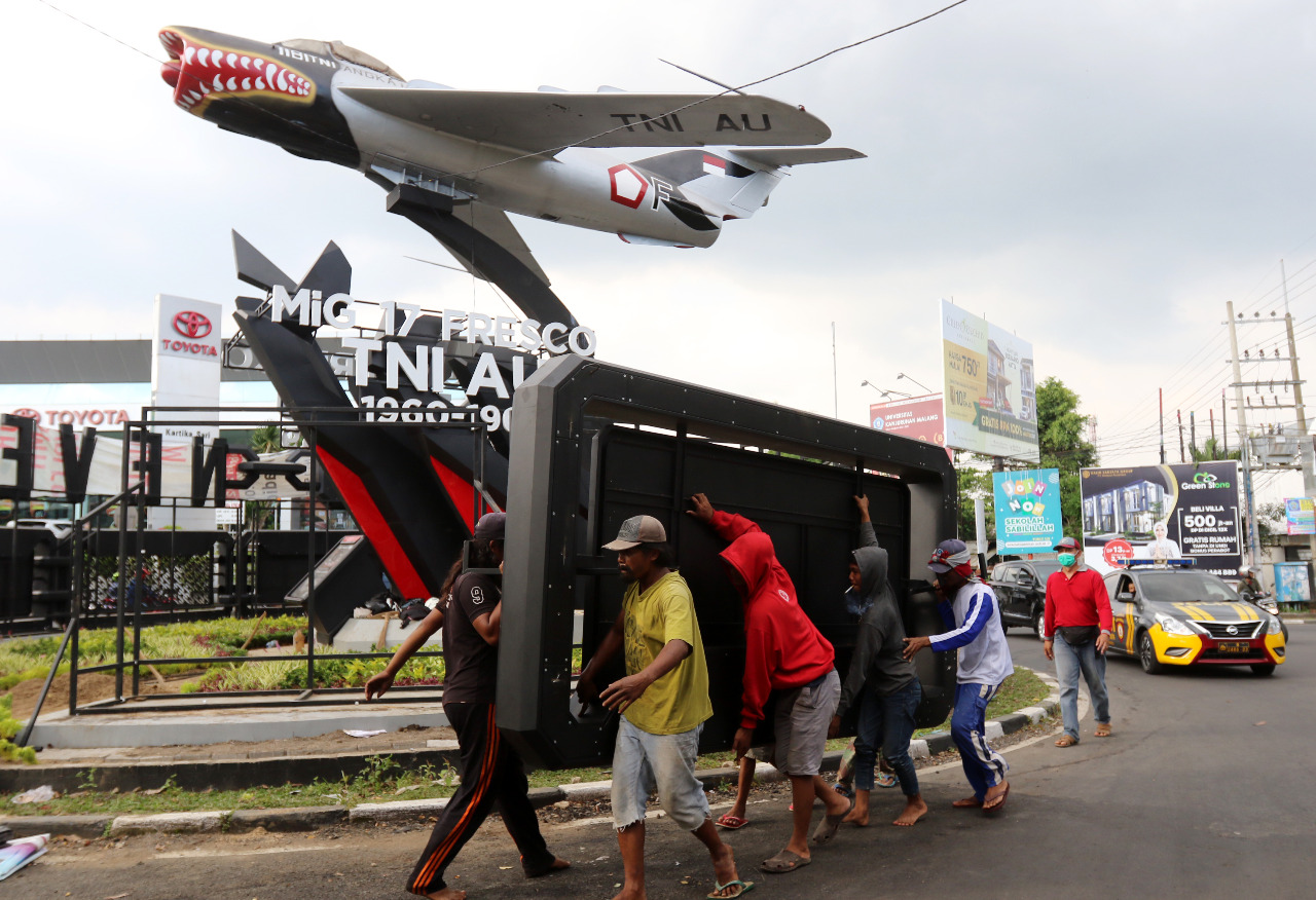 Sejumlah pekerja tengah membongkar iklan reklame di Monumen Pesawat Soehat. (Darmono/Radar Malang)