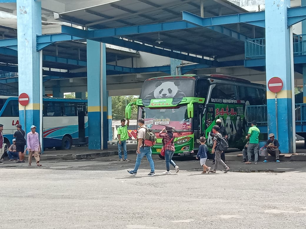 MUDIK: Sejumlah calon penumpang melintas di depan armada bus di Terminal Arjosari. (Aditya Novrian/Radar Malang)