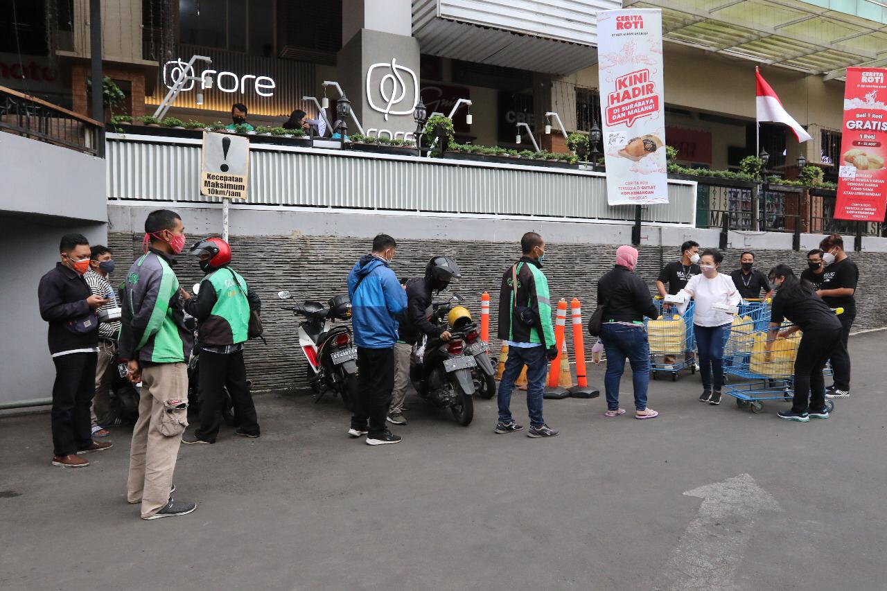 Mall Director Malang Town Square (Matos), Fifi Trisjantie (kemeja putih) membagikan nasi kotak kepada para ojol di depan Matos, Kamis (12/8). (Darmono/Radar Malang)
