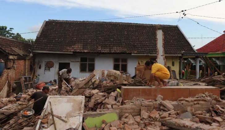 Seorang warga membersihkan puing-puing bangunan rumah yang runtuh akibat bencana gempa pada April lalu. (Dok radar Malang)
