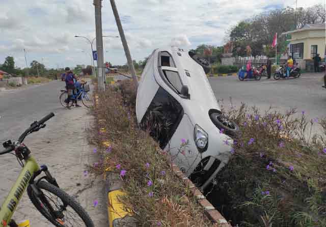 Kondisi mobil Ayla yang nyungsep di saluran air di depan kompleks Perumahan Pondok Permata Suci (PPS) 2, Gresik Minggu pagi (12/9). (Sholahuddin/Jawa Pos)