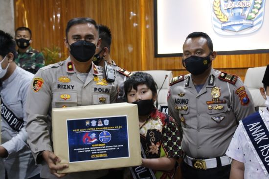 Wakapolres Malang Kompol Rizky Tri Putra bersama AKP Agung Fitriansyah saat menyerahkan bantuan kepada anak asuh Polres Malang. (Ubaidillah/Radar Malang)