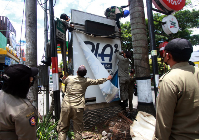 Petugas Bapenda dan Satpol PP Kota Malang melakukan pembongkaran reklame nakal di kawasan Jalan Soekarno Hatta, Kota Malang, Senin (18/10). (Suharto/Radar Malang)