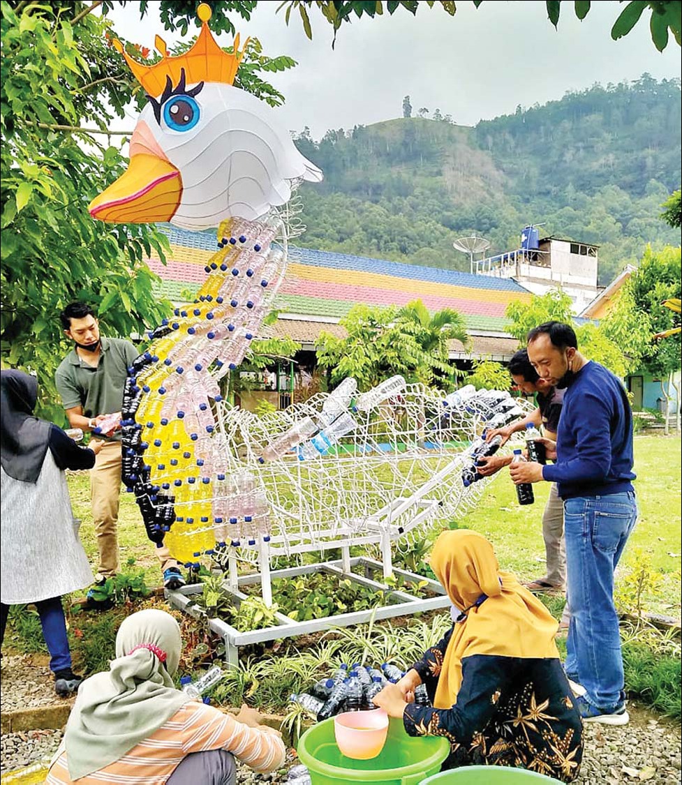 Para guru di SDN 3 Songgokerto membuat kreasi patung angsa dari bahan daur ulang, Kamis (14/10). (Anugrah/Radar Malang)