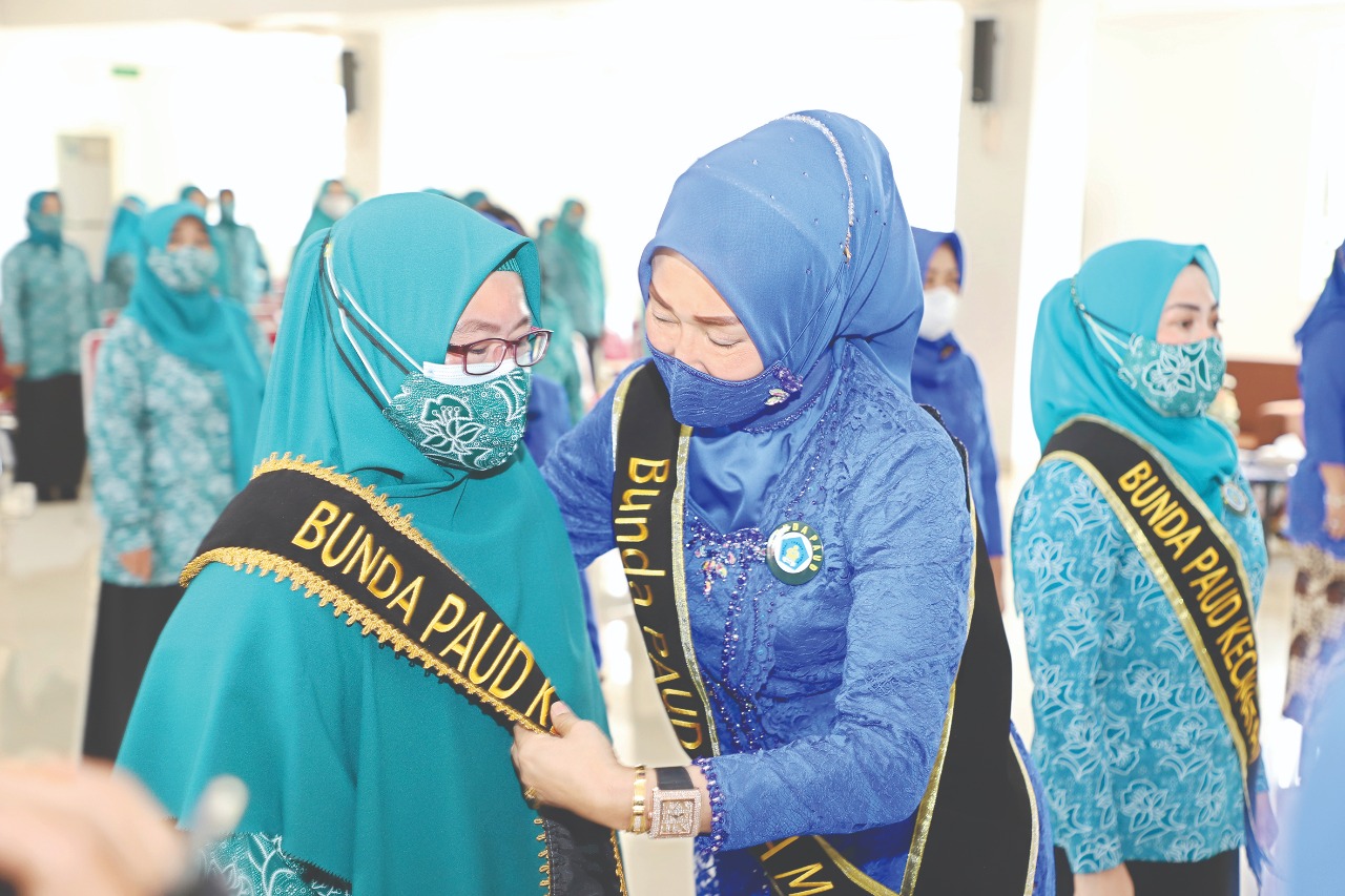 Bunda PAUD Kota Malang Widayati Sutiaji memasang kain selempang ke salah satu pengurus Pokja Bunda PAUD Kota Malang Periode 2021-2024, Kamis (7/10). (Rofia/radar malang)