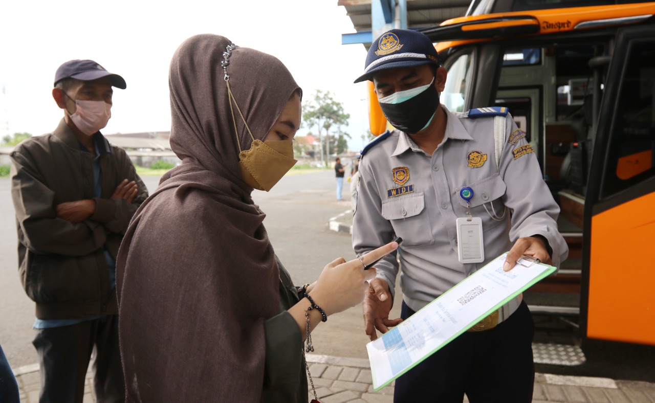 Petugas di Terminal Arjosari membimbing penumpang untuk memindai QR Code aplikasi PeduliLindungi. Syarat itu wajib dipenuhi tiap calon penumpang. (Darmono/Radar Malang)