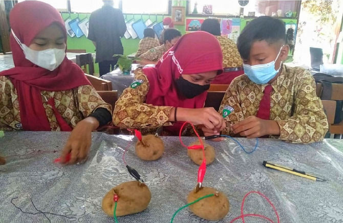 Siswa-siswi kelas 6 mempraktikkan cara memanfaatkan kentang menjadi energi listrik, kemarin (22/10) (Suharto/Radar Malang)
