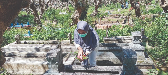 Seorang peziarah sedang menyekar di salah satu pemakaman di Kota Batu. (Nugraha/Radar Malang)