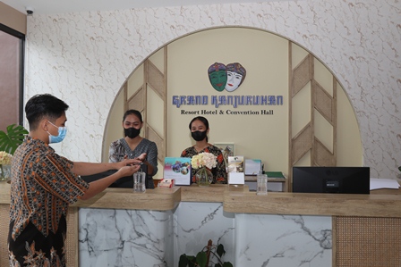 PROKES: Resepsionis Grand Kanjuruhan Resort Hotel and Convention Hall mempersilakan tamu untuk mensterilkan tangannya menggunakan cairan hand sanitizer. Kini mereka bersiap program promo untuk lebaran. (Ist)