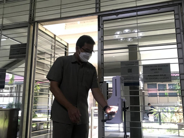 Seorang civitas academica UM melakukan sterilisasi sebelum memasuki kawasan perkuliahan. (Darmono/Radar Malang)