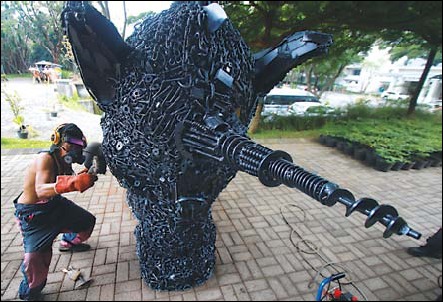 Soemarsono Ono Gaf memberi sentuhan akhir karyanya berupa patung kepala unicorn yang dibuat dari aneka jenis besi bekas. (Suharto/Radar Malang)