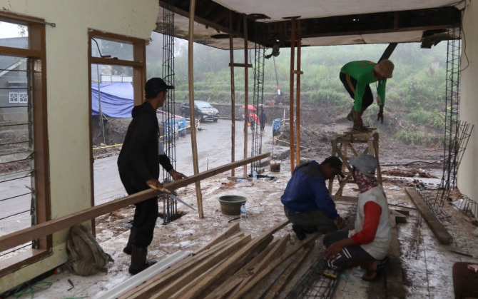 DAPAT BANTUAN MATERIAL: Relawan rekonstruksi BPBD Kota Batu membantu  perbaikan rumah Yasmari di Dusun Kliran, Desa Bulukerto, kemarin (16/11)