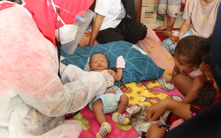 Bidan desa memeriksa bayi di tenda pengungsian Kabupaten Malang