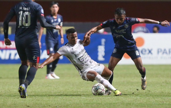 SKOR KACAMATA: Ridwan Tawainella (kanan) berebut bola dengan gelandang Bali United Eber Bessa di laga Minggu malam (5/12/2021). (Ahmad Khusaini / Jawa Pos)
