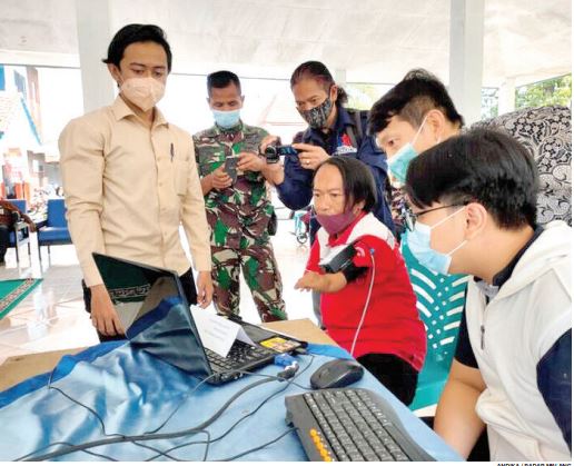 SANGAT MEMBANTU: Penyandang tuna daksa mencoba mouse difabel buatan tim peneliti Universitas Ma Chung. (andika/radar malang)