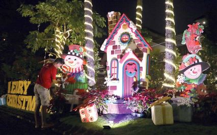 BERNUANSA NATAL: Dekorasi berupa tulisan “Merry Christmas” di taman depan rumah itu menyambut setiap tamu di rumah pasangan Andreas dan Ita Wulan. (darmono/radar malang)