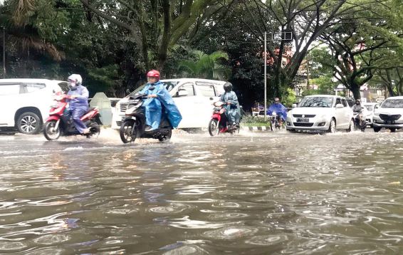 TERSUMBAT SAMPAH: Sejumlah pengendara melintas di ruas Jalan Soehat yang kebanjiran, siang kemarin. (Aditya Novrian/Radar Malang)