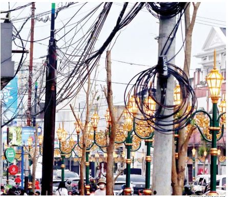 TAK ENAK DIPANDANG: Kabel bergelantungan dan tidak tertata rapi terlihat mengganggu pandangan di kawasan Kajoetangan Heritage. (darmono/radar malang)
