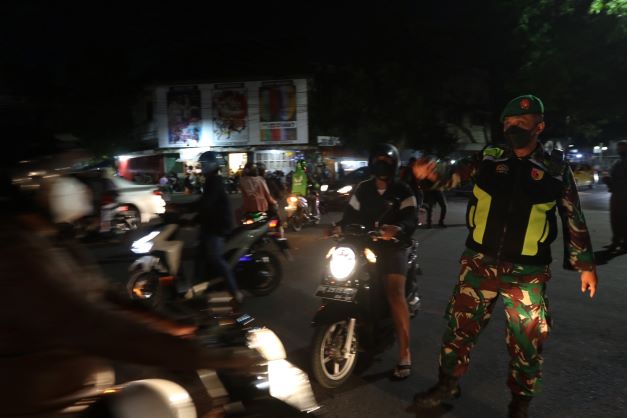 DAMPAK COVID: Petugas Dinas Perhubungan Kota Malang mengatur pengguna jalan raya untuk tidak melintasi Jalan Soekarno-Hatta tadi malam. (darmono/radar malang)