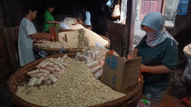 TETAP PRODUKSI: Pekerja di Kampung Tempe Sanan sedang mengolah kedelai untuk menjadi tempe. Saat ini, harga bahan baku kedelai berada di angka Rp 11.500 per kilogram. Padahal sebelumnya, harga kedelai hanya Rp 9 ribu per kilo gram. (Suharto/Radar Malang)
