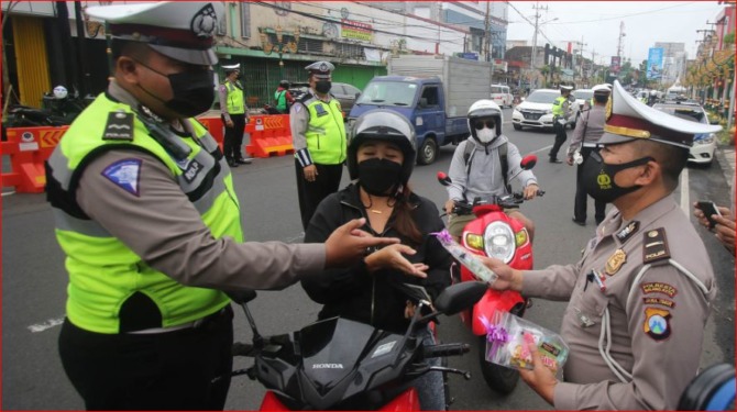 SELAMAT: Kanit Kamsel Satlantas Polresta Malang Kota Iptu M. Sochib saat meyerahkan bingkisan valentine berisi permen cokelat dan paket prokes kepada salah satu pengendara di Kajoetangan Heritage, Senin (14/2/2022).   (Suharto/radar malang)