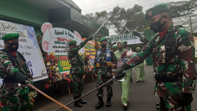 SELAMAT DATANG: Letnan Kolonel Kav Heru Wibowo Sofa SH bersama istri disambut tradisi pedang pora di halaman Makodim 0833/Kota Malang. (Pen Kodim  0833 Kota Malang For Radar Malang)