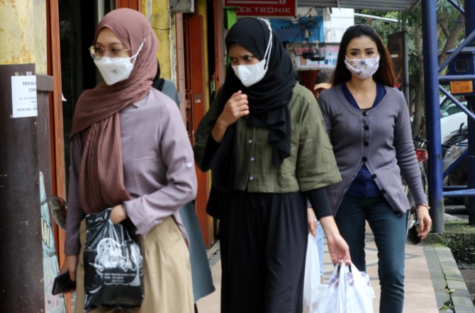 TAAT PROKES:  Tiga warga  Kota Malang  berjalan  di depan  kawasan  Malang  Plaza sambil  mengenakan  masker  kemarin.  Selain vaksin,  masker masih  menjadi  andalan untuk  mengendalikan  penyebaran  Covid-19. (Darmono/Radar Malang)