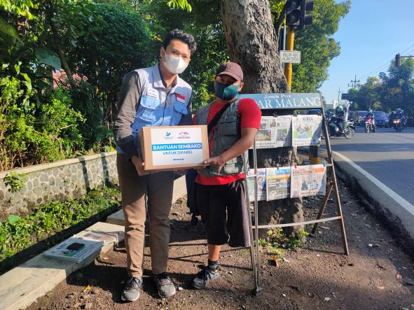 BERKAH: Perwakilan Sahabat Mustahiq saat memberikan paket sembako untuk loper difabel JP Radar Malang. (SAHABAT MUSTAHIQ FOR RADAR MALANG)