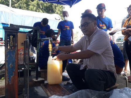 BAKSOS: Pemilik Minyak Goreng (Kuda Group) Toni Surya Hartanto mengisi jeriken berisi migor curah, untuk didistribusikan kepada warga yang antre di Pasar Tumpang, kemarin.