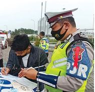 TAK PUNYA SIM: Abdul Hamid (kiri) diberi surat tilang karena telah menerobos masuk ke pintu tol Karanglo, kemarin siang (6/5). (SUHARTO/RADAR MALANG)