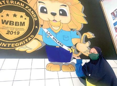 KREATIF: Restu Eka Briantitasari menunjukkan salah satu karya lukis yang terpajang di sudut Lapas Perempuan Kelas IIA Malang. (FAJAR ANDRE SETIAWAN/RADAR MALANG))