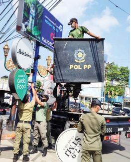 PENERTIBAN: Tim Satpol PP Kota Malang menurunkan papan reklame jenis neon box di kawasan Kajoetangan Heritage kemarin.(SATPOL PP KOTA MALANG FOR RADAR MALANG)