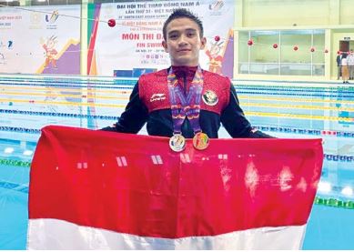 ISTIMEWA: Bima Dea Sakti Antono merentangkan bendera merah putih setelah berhasil meraih dua medali cabang olahraga fin swimming di SEA Games Vietnam. (Bima Dea Sakti Antono For Radar Malang)