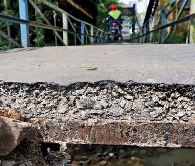 BUTUH PERHATIAN: Lubang pada jembatan gantung di Kelurahan Pisang Candi, Kecamatan Sukun ini mulai menganga. Total ada tiga lubang di jembatan tersebut.