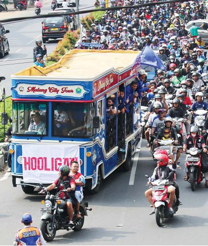 TAMBAHAN MOTIVASI: Rombongan pemain Arema FC turut diarak ribuan Aremania saat melintas di Jalan A. Yani, Kecamatan Blimbing. Bus yang mengangkut pelatih dan pemain Singo Edan itu bergerak menuju mess tim di daerah Sukarno-Hatta.
