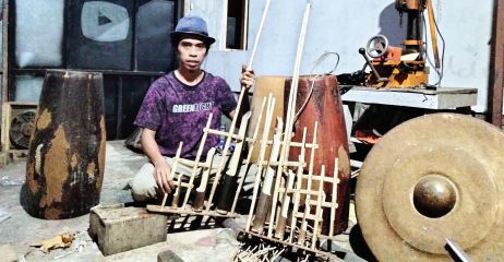TELATEN: Arik Sugiyanto sedang menggarap pesanan pembuatan alat musik tradional di tempat kerjanya kemarin malam.