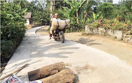 MENUJU PANTAI: Warga menggunakan sepeda motor melintas di jalan cor beton yang baru separo dikerjakan di Desa Sumbertangkil, Kecamatan Tirtoyudo.