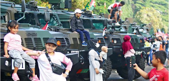 DARI RAKYAT UNTUK RAKYAT: Sejumlah warga bersama keluarga memanfaatkan kesempatan berfoto dengan latar tank milik TNI Angkatan Darat di Lapangan Brawijaya Rampal, Klojen, Kota Malang, kemarin