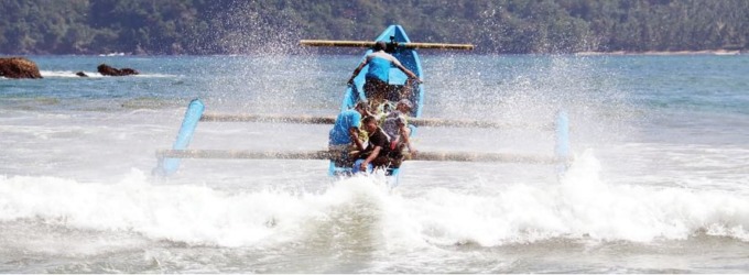 TERJANG OMBAK: Perahu nelayan berusaha melewati ombak di Pantai Lenggoksono sambil membawa sesaji yang akan dilarung ke tengah laut, kemarin (15/8).