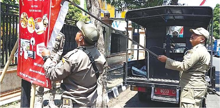 belum bayar: tim satpol pp menurunkan reklame yang izinnya telah habis, kemarin (22/8). (SATPOL PP KABUPATEN FOR RADAR KANJURUHAN )