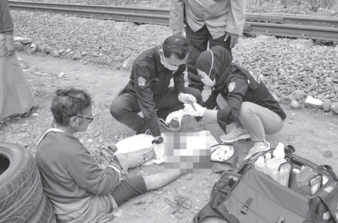 TERTOLONG: Tim medis mengobati jari kaki Samini yang terlindas roda kereta api di perlintasan Jalan W.R. Supratman kemarin (5/9). (POLSEK KLOJEN FOR RADAR MALANG)
