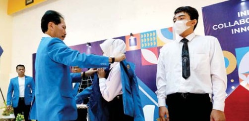 PENGENALAN KAMPUS: Rektor ITN Prof Dr Eng Ir Abraham Lomi MSEE (kiri) memakaikan jas almamater kepada salah satu mahasiswi baru, (12/9). (ITN Malang For Radar Malang)
