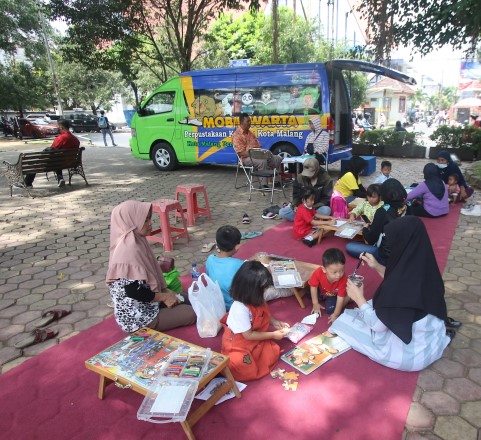 WISATA SAMBIL MEMBACA: Wisatawan di Alun-Alun Merdeka Kota Malang bisa menikmati bacaan yang disediakan Perpustakaan Keliling, kemarin. (Suharto/Radar Malang)
