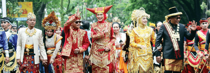 BANGKIT BERMARTABAT: Wali Kota Malang Sutiaji bersama istrinya, Widayati Sutiaji, tampak mengenakan pakaian adat Minang. Diiringi para ASN Pemkot Malang yang juga mengenakan pakaian adat, mereka berjalan kaki mulai dari Jalan Basuki Rahmat hingga Jalan Se