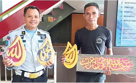 HASIL BIMBINGAN KERJA: Sunardi (kanan) didampingi petugas Lapas Lowokwaru menunjukkan salah satu karya kaligrafi, kemarin. (BIYAN MUDZAKY HANINDITO/RADAR MALANG)