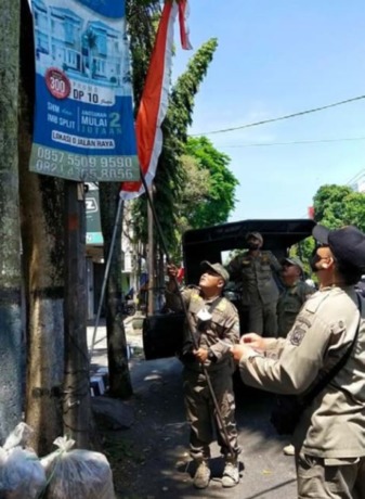 DITURUNKAN: Petugas Satpol PP Kabupaten Malang melakukan penertiban reklame di kawasan Kota Kepanjen.