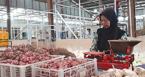 TUNGGU PEMBELI: Misti, pedagang bawang merah di Pasar Sayur mengeluhkan sepinya pembeli. (AFIFAH RAHMATIKA/RADAR BATU)